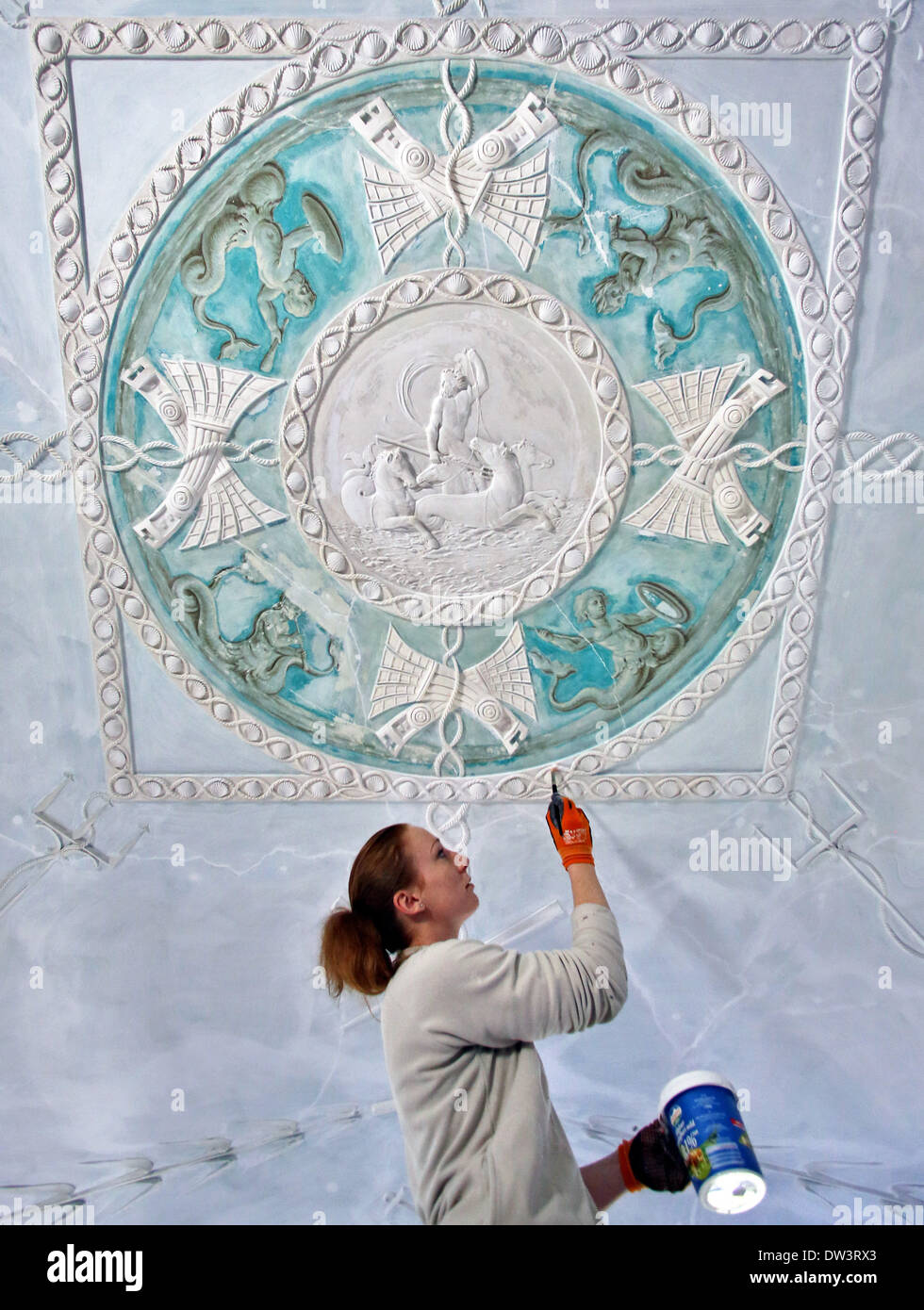 Restorer Michelle Eicke paints primer on the stucco ceiling in the preserved suite of Marshall Georg Heinrich von Berenhorst, at Woerlitz Palace in Woerlitz, Germany, 24 February 2014. There are six other similar suites of two rooms in the palace commissioned by Prince Leopold Friedrich Franz von Anhalt-Dessaut. They are being restored until 2016. The rooms were used by the prince and his family as well as Marshall Berenhorst and the architect Erdmanndorff. The palace is part of the UNESCO World Cultural Heritage and is an example of German neo-classicism. Photo: Jan Woitas Stock Photo