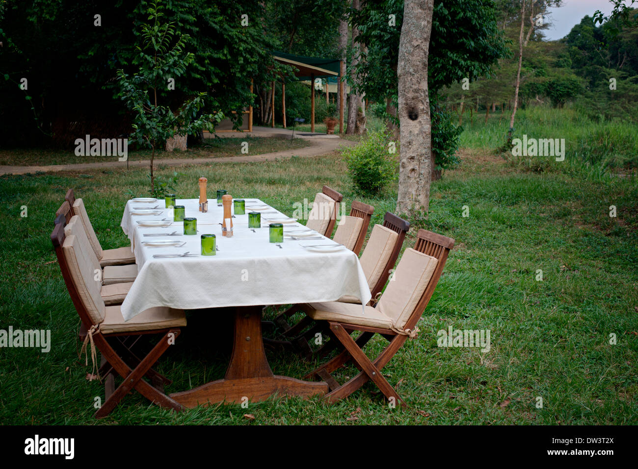 Al Fresco Dining - Seating for 8 eight outdoors in the evening, Uganda. Empty chairs. A grassy area. Stock Photo