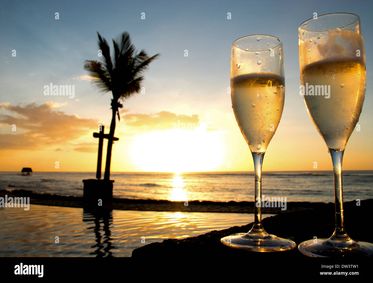 two glasses on champagne or sparkling wine next to a swimming pool