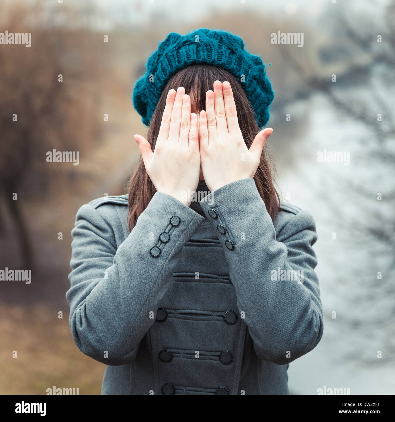 young pretty girl with hands over eyes outdoors Stock Photo