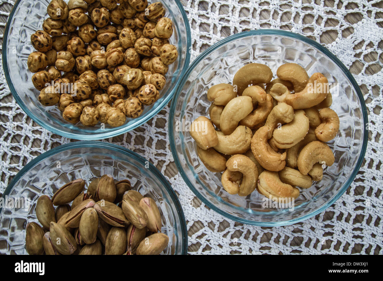 Assorted nuts in glass bowls on hand knitted tablecloth background Stock Photo