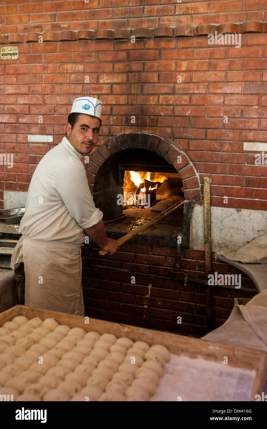 Chef prepares pita bread to cook in wood burning oven in restaurant in