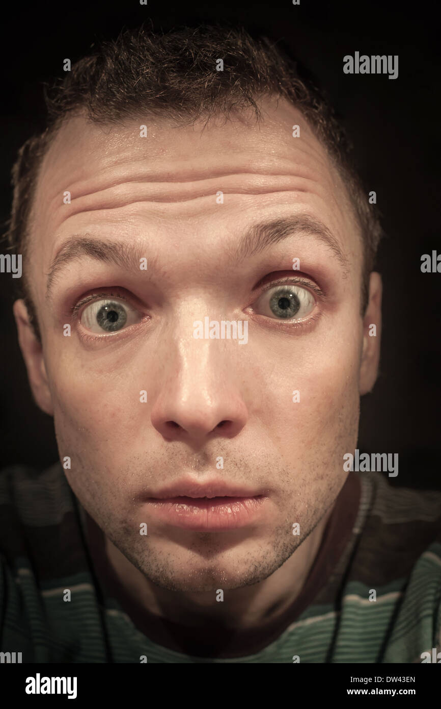 Young shocked Caucasian man portrait on dark background Stock Photo