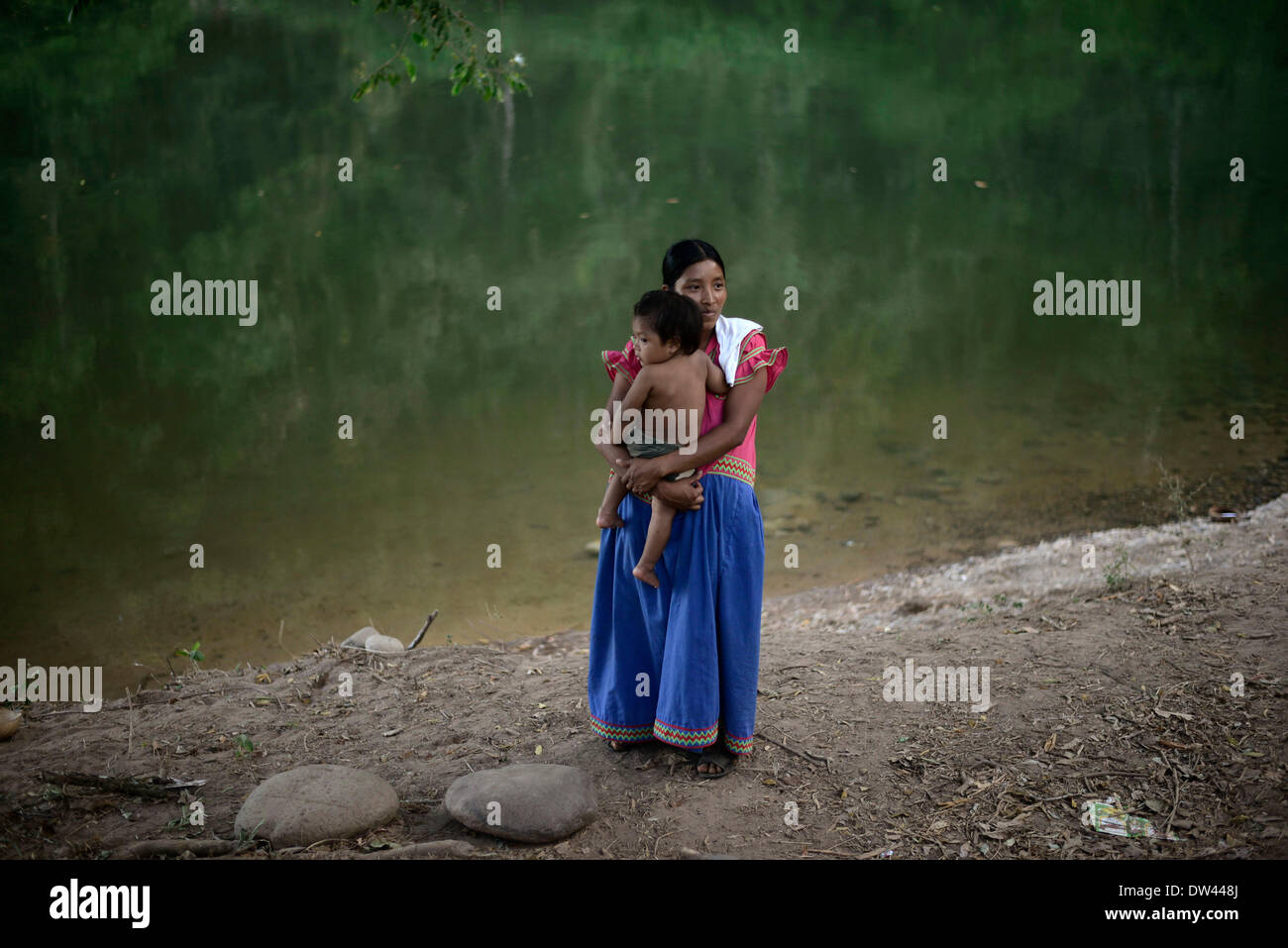 (140227) -- NGABE BUGLE REGION, Feb. 27, 2014 (Xinhua) -- A woman of the Ngabe Bugle ethnic group carries her baby in a camp near the Tabasara river bank in the Ngabe Bugle indigenous region, 450 km west of Panama City, capital of Panama, on Feb. 24, 2014. The Ngabe Bugle indigenous region is located in the western region of Panama, and covers an area of 6,968 square km, with 91 per cent of its population living in extreme poverty. Native leaders of the Ngabe Bugle region declared a 'national alert', because of the eviction notice issued by a company which is developing the hydro-electric proj Stock Photo