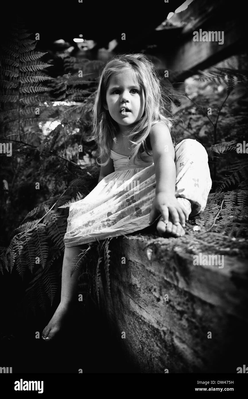 Cute Toddler Girl sitting in an interesting setting with white dress. Stock Photo