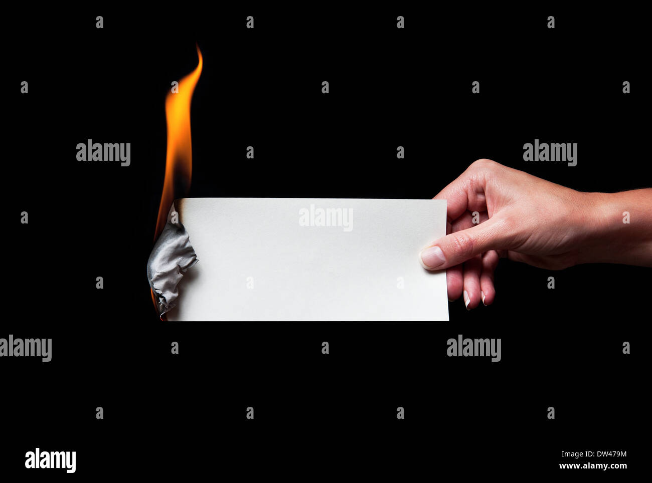 Woman's hand holding a burning paper - enter own caption. Stock Photo