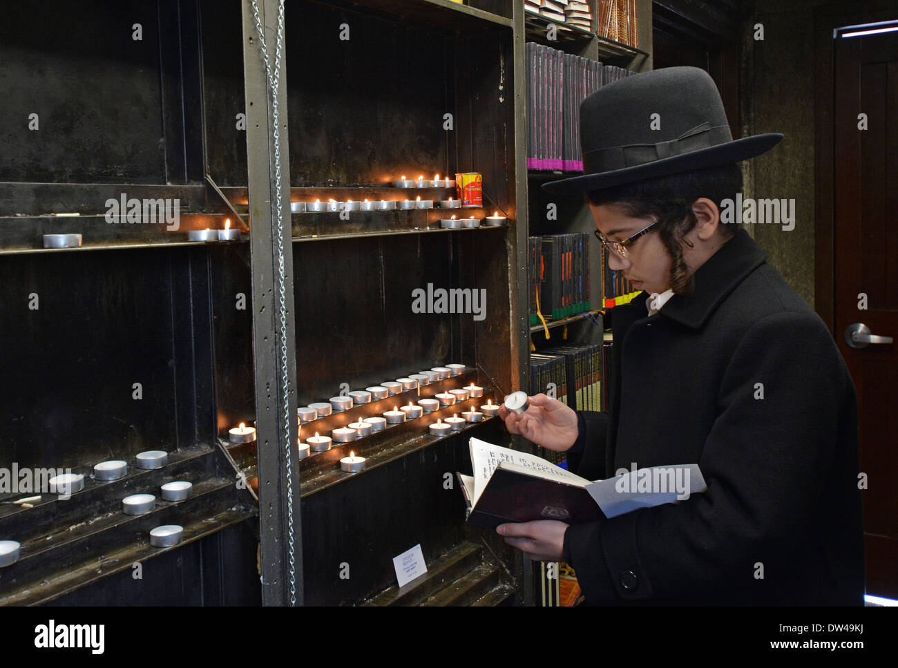 Religious Jewish boy lights a candle prior to visiting the grave of the Lubavitcher Rebbe in Cambria Heights, Queens, New York Stock Photo
