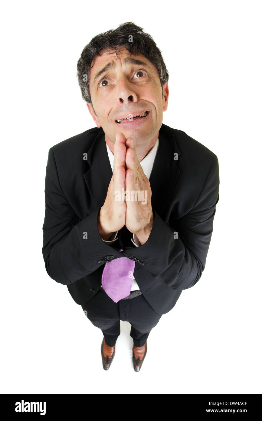 Humorous high angle full length portrait of an expressive desperate businessman praying in supplication pleading for help Stock Photo