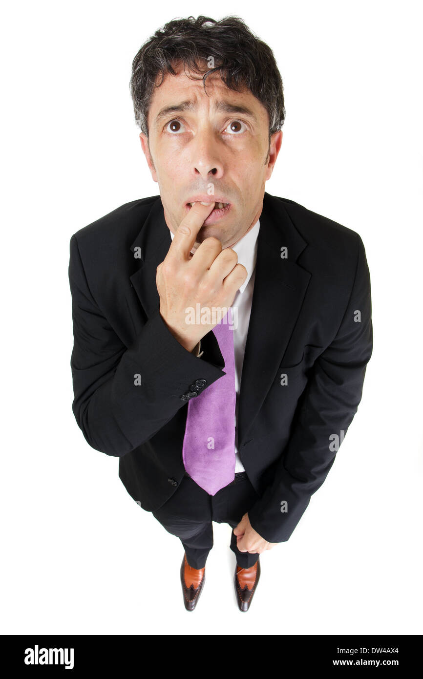 comic portrait from a high perspective of a forgetful or ignorant businessman standing with his finger clasped between his teeth Stock Photo