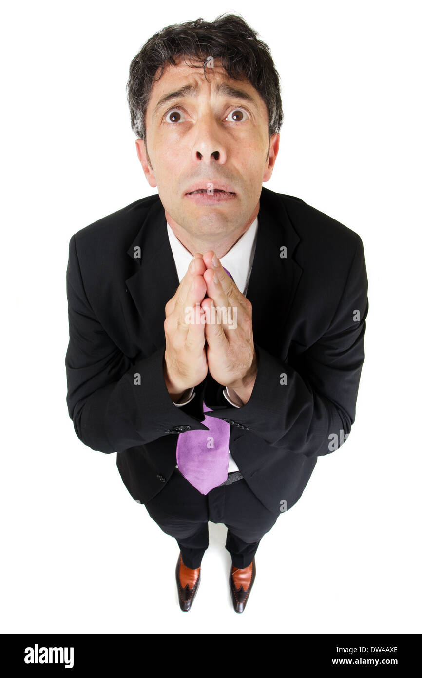 Humorous high angle full length portrait of an expressive desperate businessman praying in supplication pleading for help Stock Photo