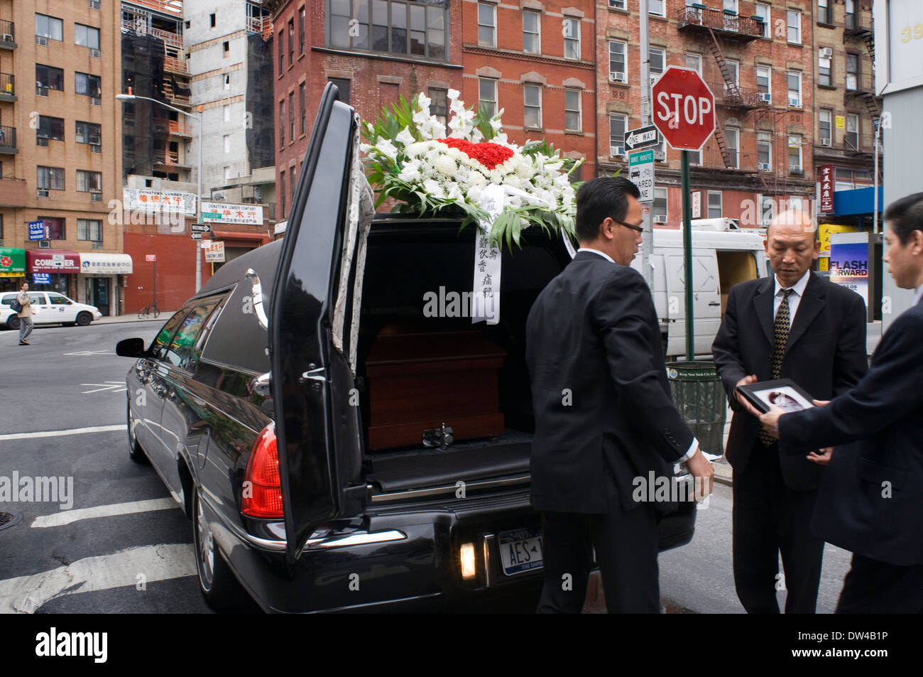 A funeral in Manhattan's Chinatown, with a hearse piled with flowers.. Funeral in Chinatown. Canal St. to the south, we enter Stock Photo