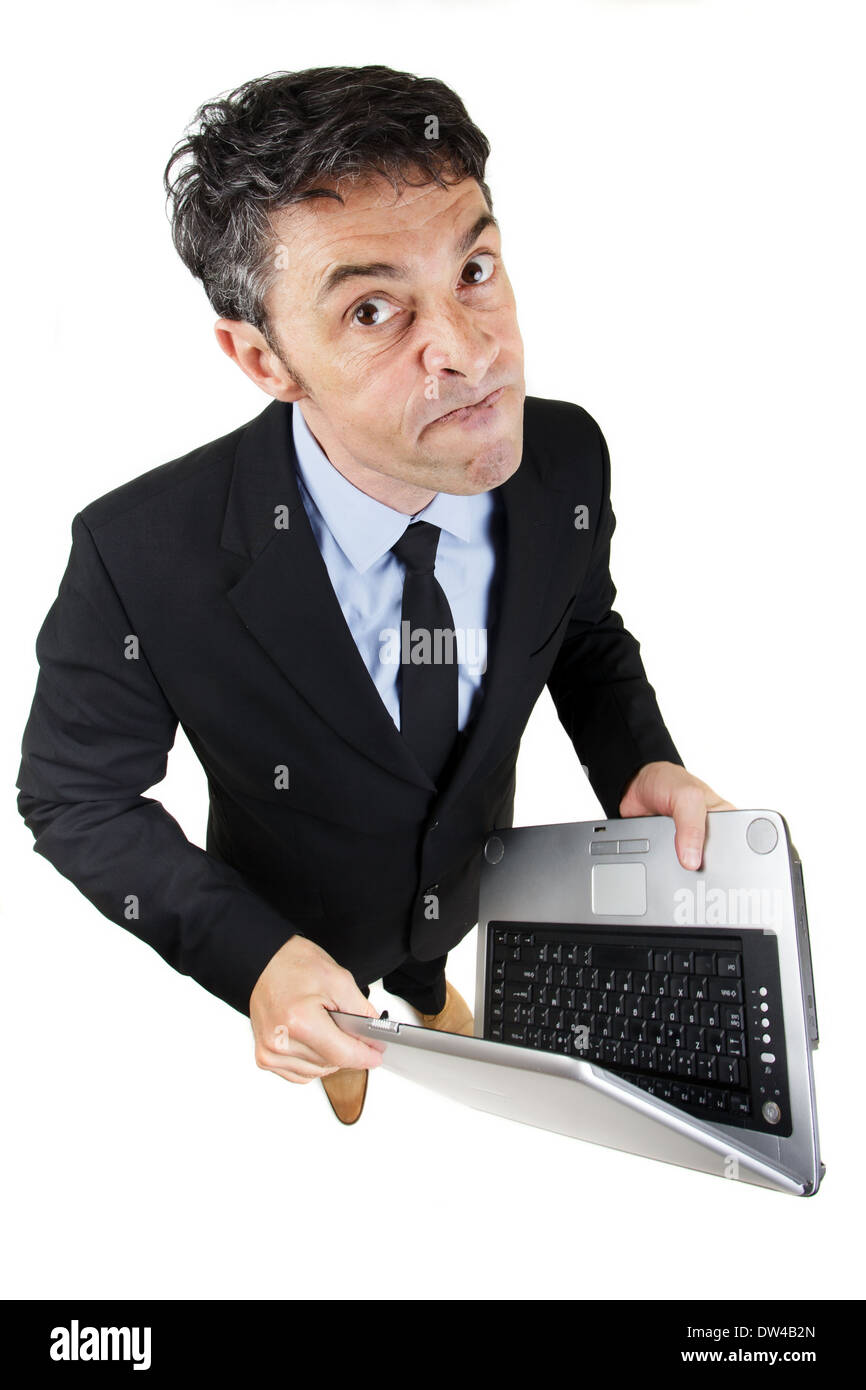 Pugnacious businessman holding a laptop computer in his hands standing looking up at the camera Stock Photo