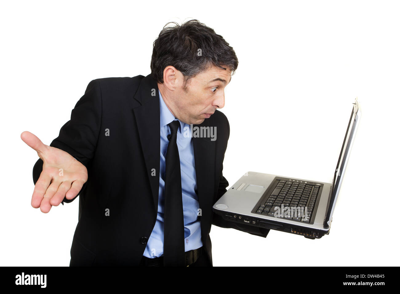 Businessman shrugging his shoulders and gesturing in disbelief or indifference as he reads his handheld laptop Stock Photo