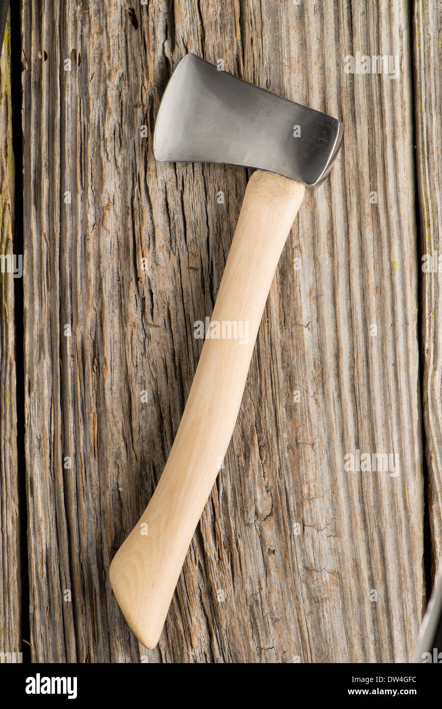 A small hatchet on a weathered wood background. Stock Photo