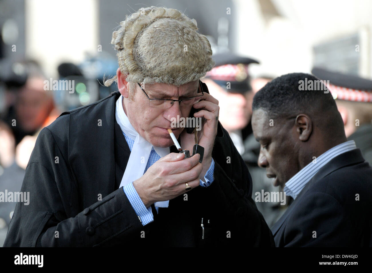 London, England, UK. Barrister outside the Old Bailey / Central Criminal Court, smoking a cigarette and on his mobile phone Stock Photo