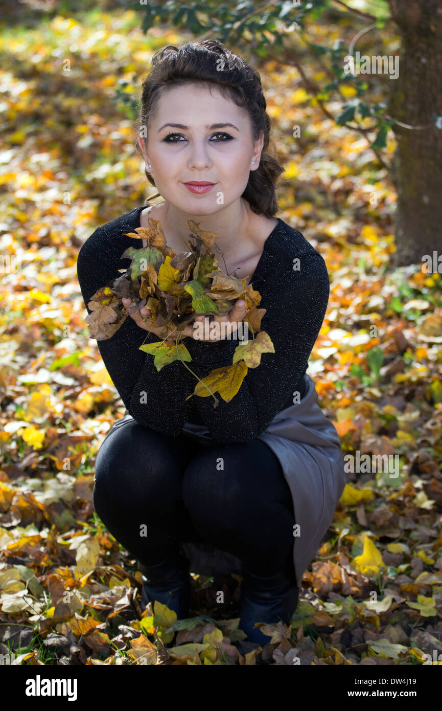 Woman holding autumn leaves in the park. Stock Photo