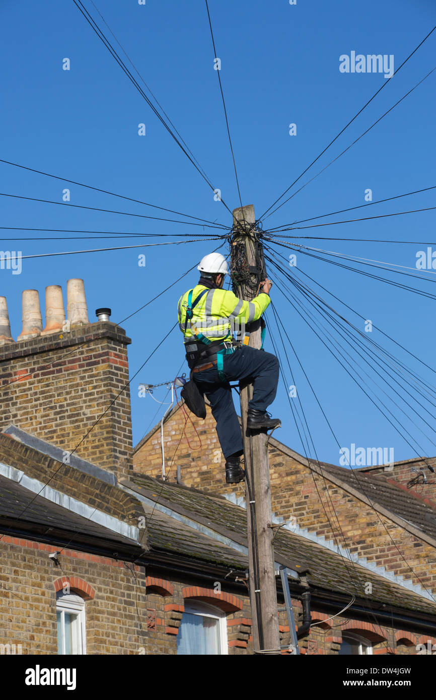 Telecommunications engineer working on an overhead telephone communications pole amongst terraced houses in London, UK Stock Photo