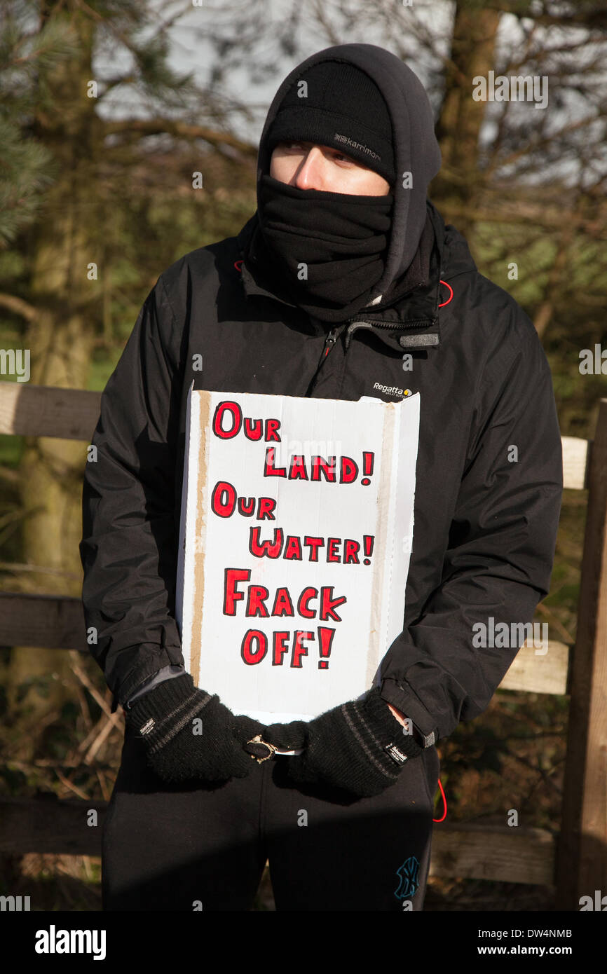 Manchester, Barton Moss, UK. 27th February, 2014. Masked protester with banner 'Our land! 'Our Water'  Frack Off!  banner as protests continue at IGAS Drilling Site.  Greater Manchester Policing operation at Barton Moss Drilling Site as protesters seek to delay and obstruct delivery vehicles and drilling equipment en-route to the controversial gas exploration site. Fracking protestors have set up a camp at Barton Moss Road, Eccles a potential methane-gas extraction site in Salford, Greater Manchester. Credit:  Mar Photographics/Alamy Live News. Stock Photo
