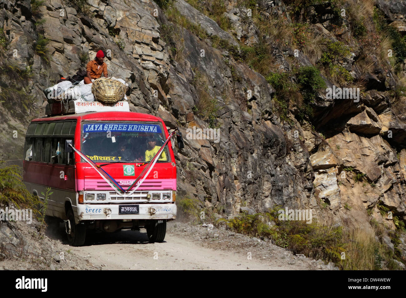 Bus with rider on top on the Annapurna road in the Gorkha region of Nepal. Stock Photo