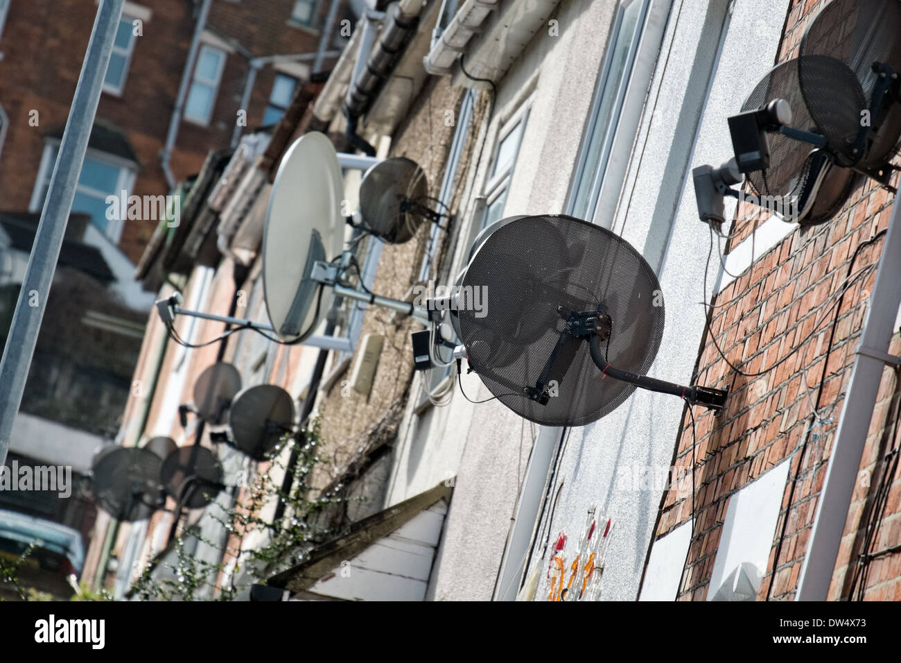 A number of satellite dishes attached to the fronts of Victorian terraced homes in the UK Stock Photo