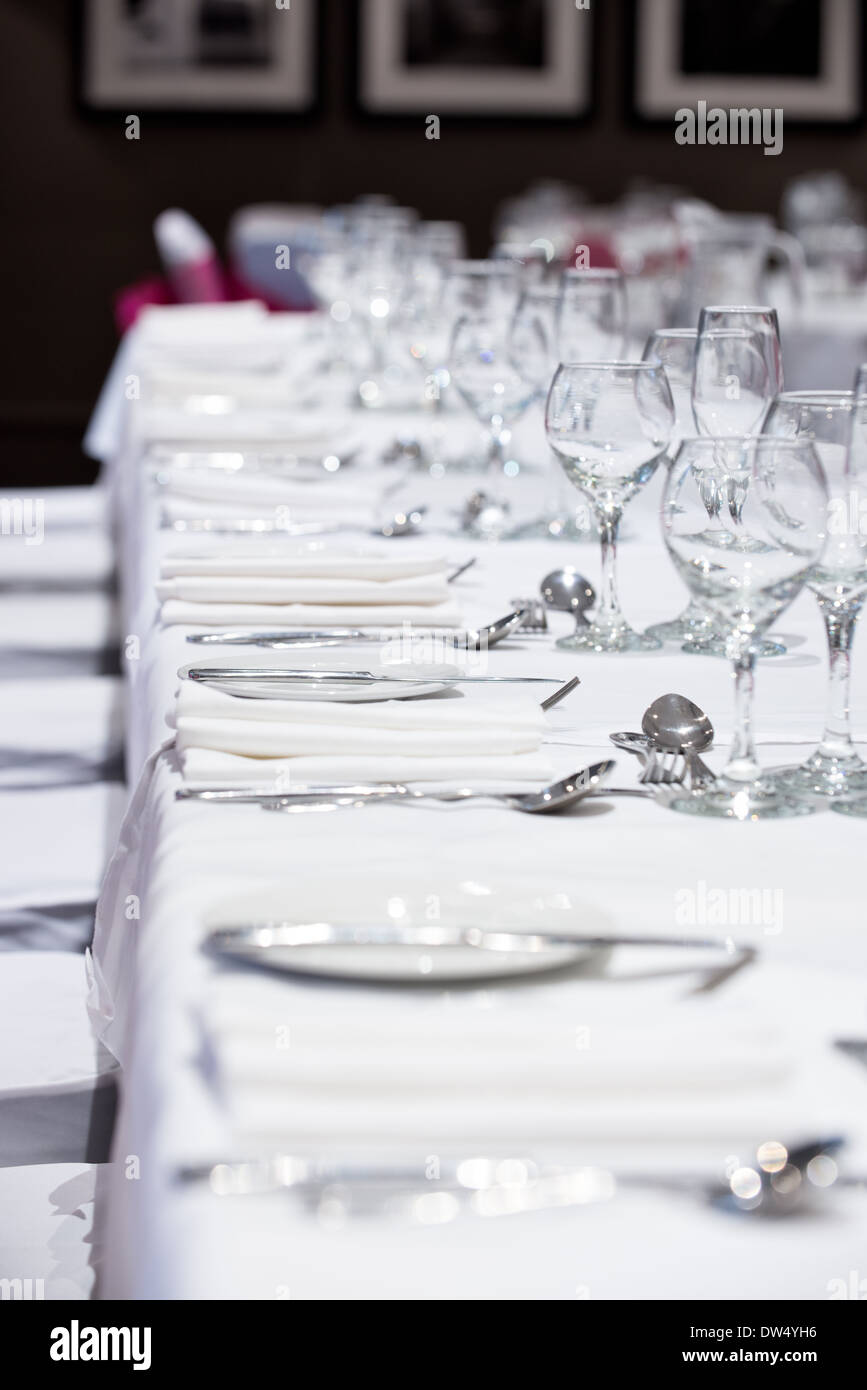 A shallow focus image of a banquet tables place settings & wine glasses awaiting the arrival of the dinners Stock Photo
