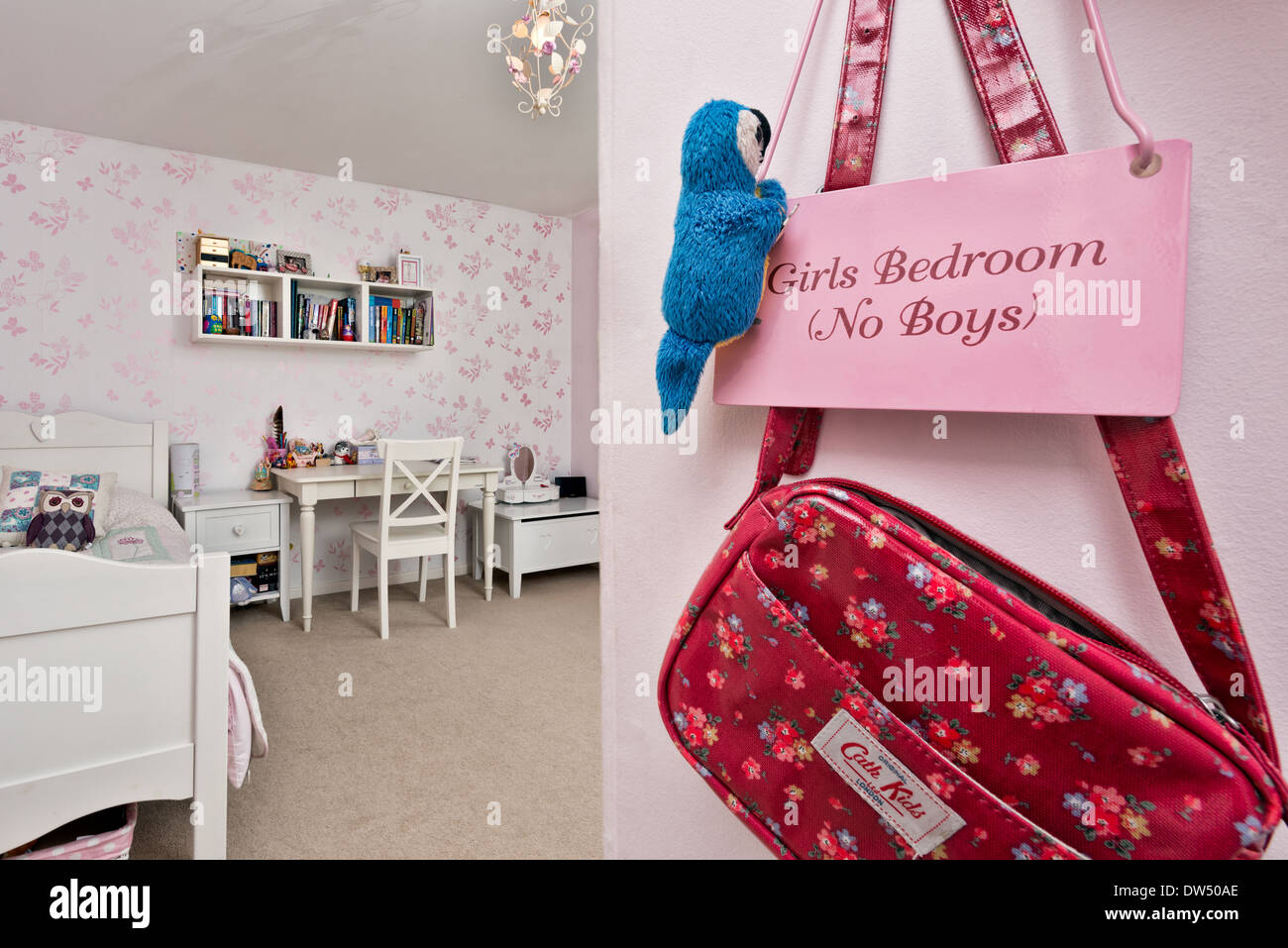 A cute pink sign hanging in kids room with a childs hanbag & plush parrot exclaiming Girls bedroom, no boys Stock Photo