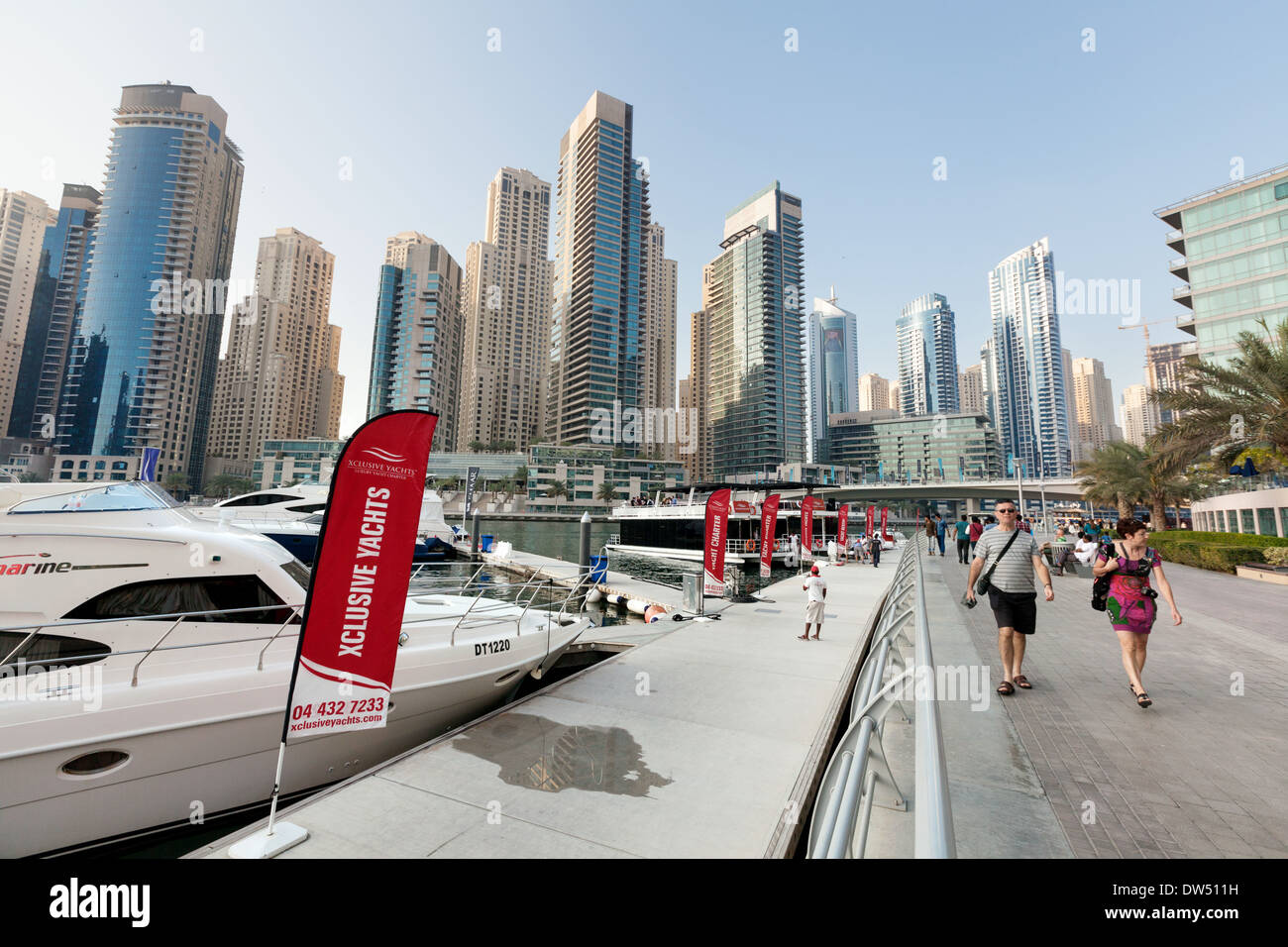 Tourists walking past yachts moored in Dubai Marina, Dubai, United Arab Emirates, UAE, Middle east Stock Photo
