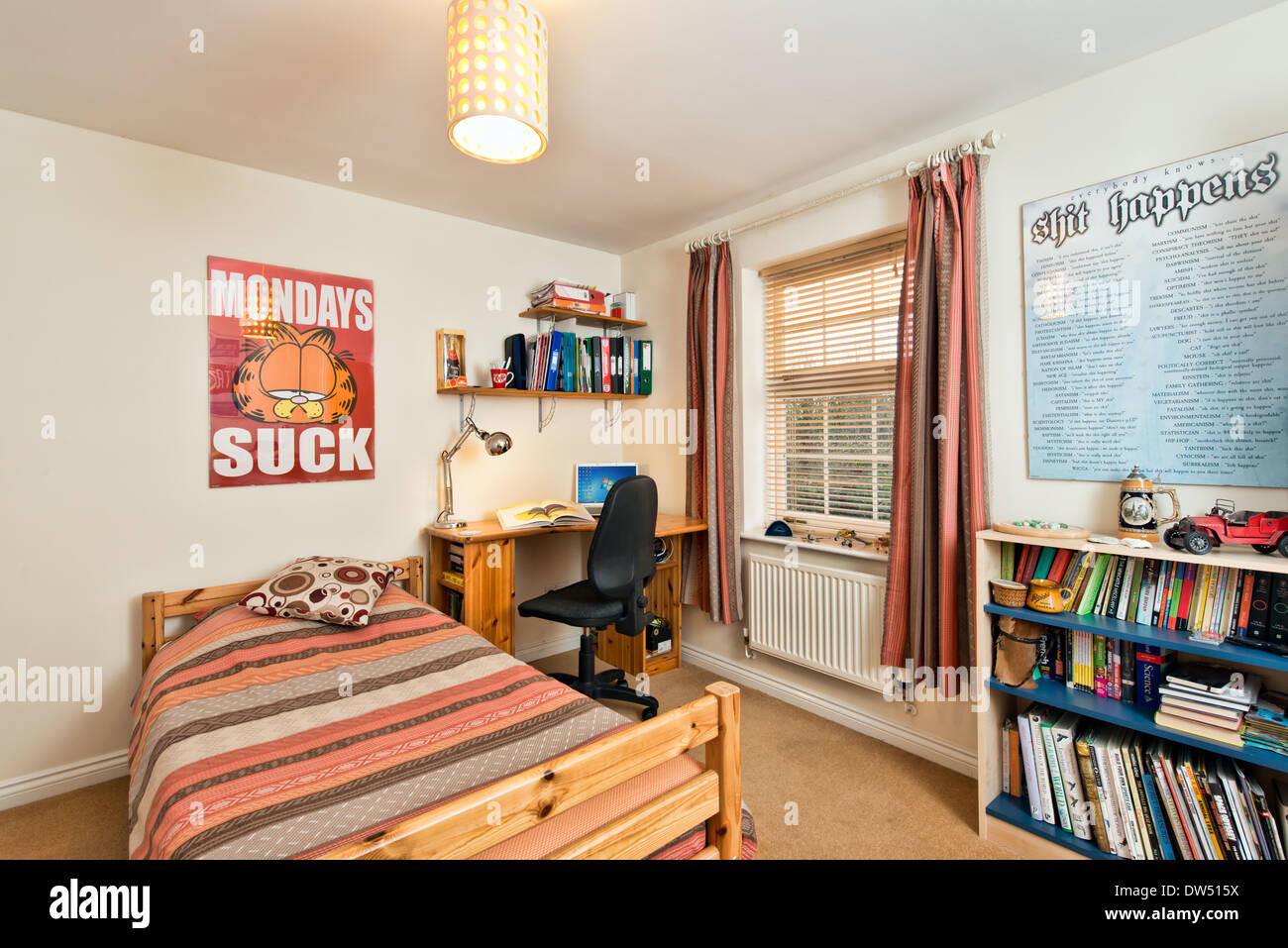 A typical teenage student bedroom or dorm accommodation with bed, books, desk & laptop computer Stock Photo