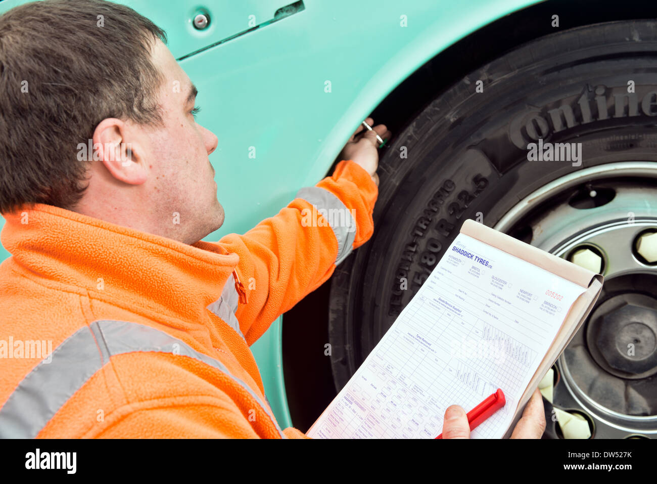 A mobile mechanic / tyre fitter checks a coaches continental tire for tread depth during a regular service & safety inspection Stock Photo