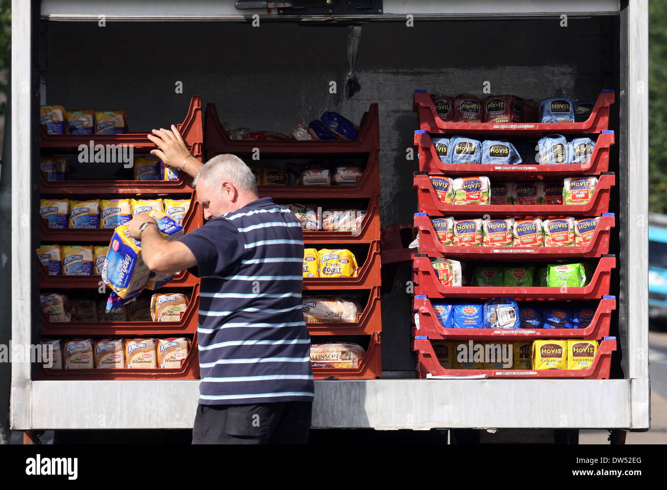 a delivery man unloads loaves of packed baked bread from the back of