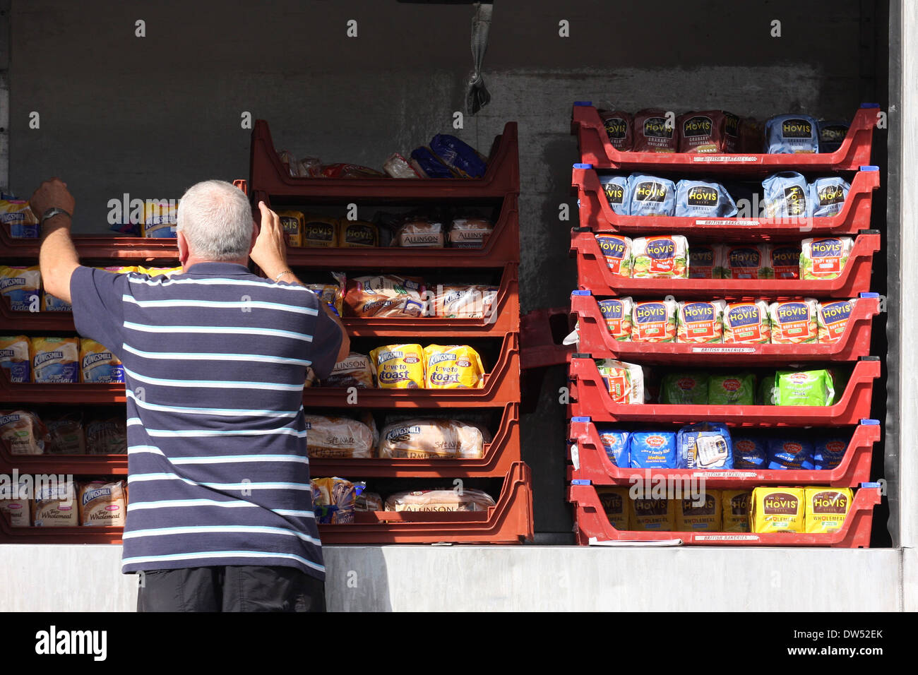 a delivery man unloads loaves of packed baked bread from the back of