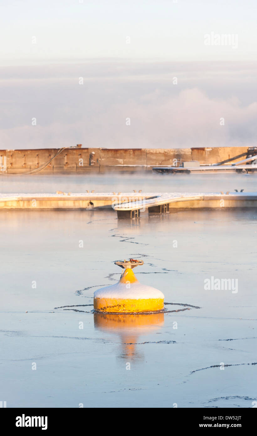 Yellow and snowy buoy in icy water Stock Photo