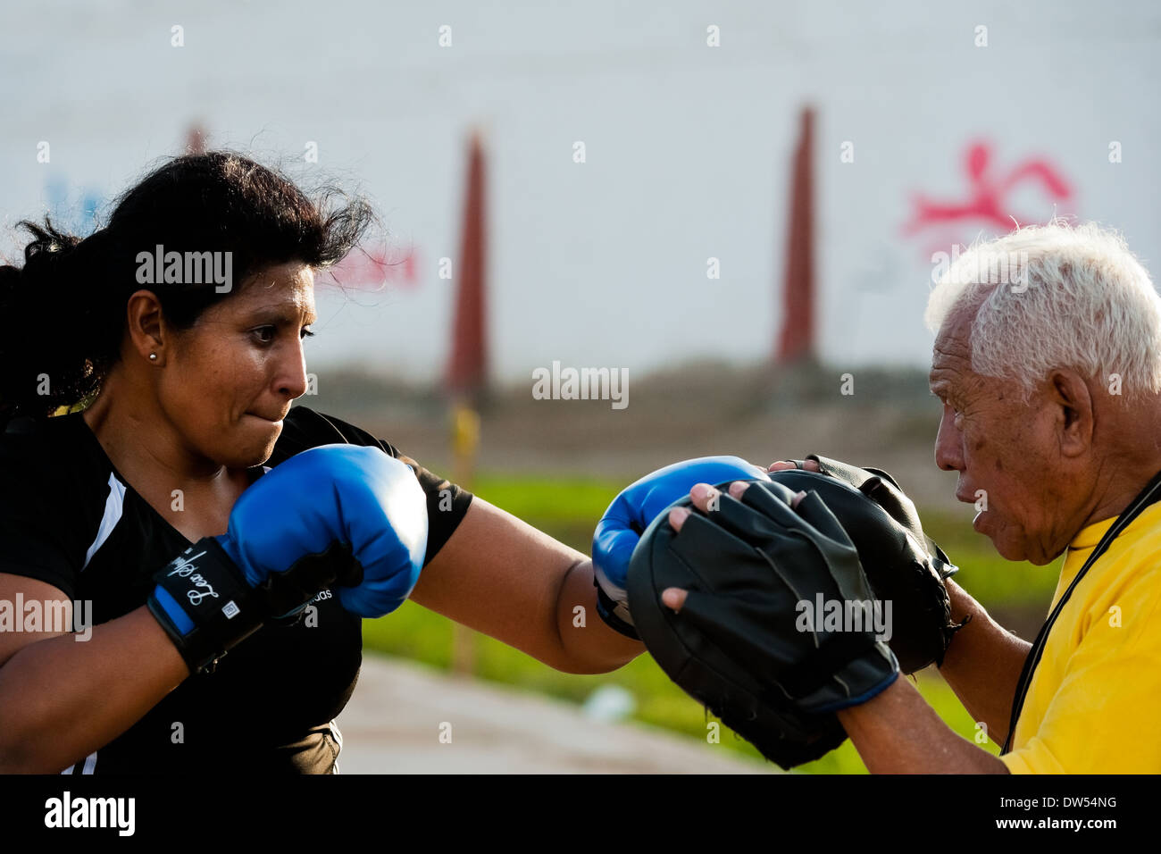 A Peruvian woman practices sparring with her coach in the outdoor boxing school in Callao, Peru. Stock Photo