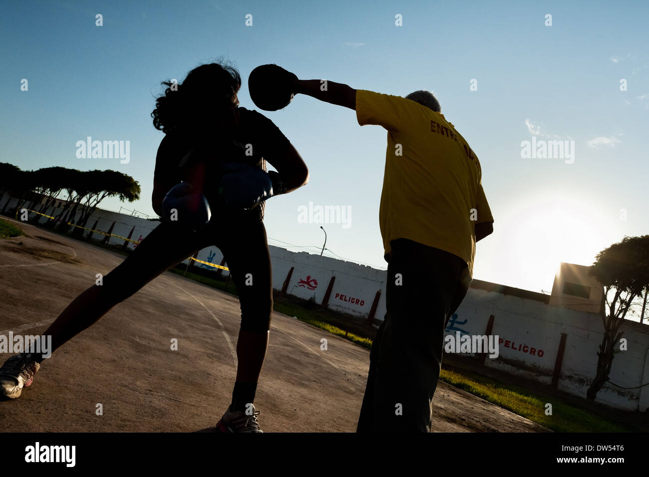 A Peruvian woman practices sparring with her coach in the outdoor boxing school  in Callao, Peru. Stock Photo