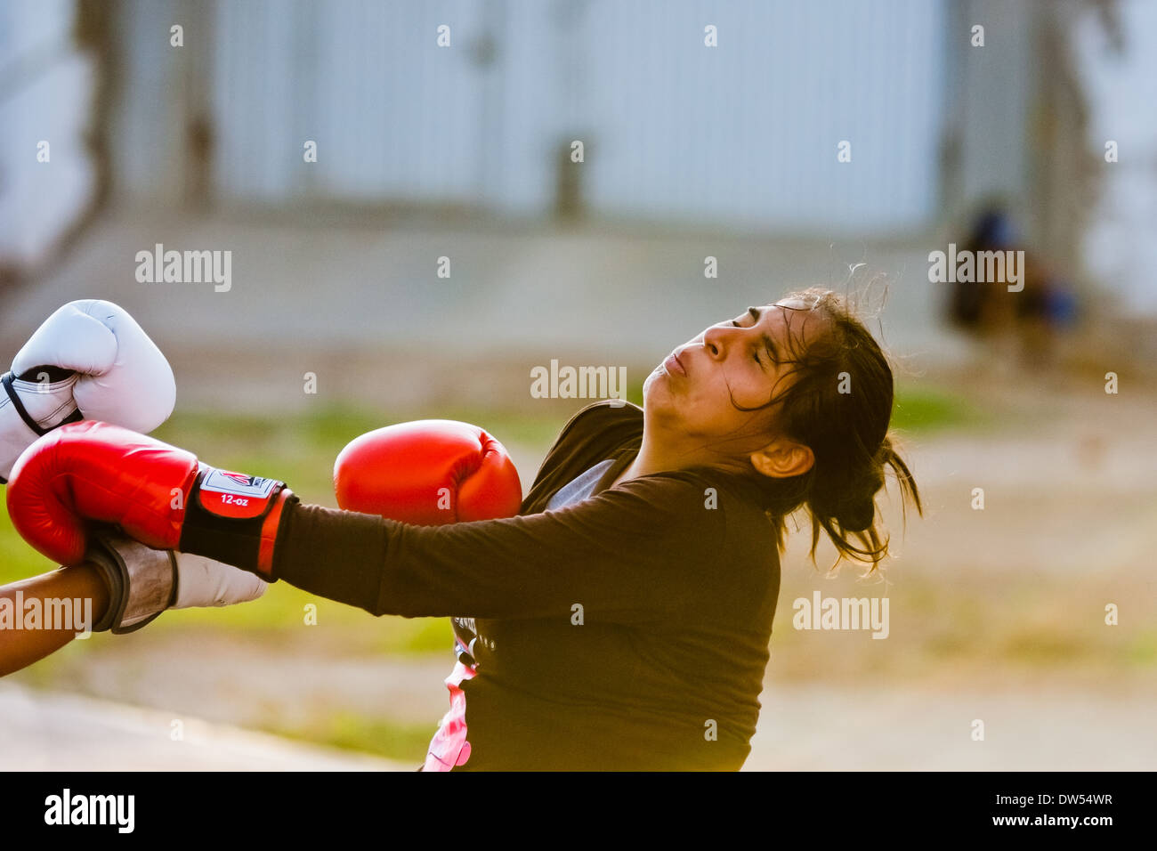 A Peruvian girl is seen being hit while training in the outdoor boxing school in Callao, Peru. Stock Photo