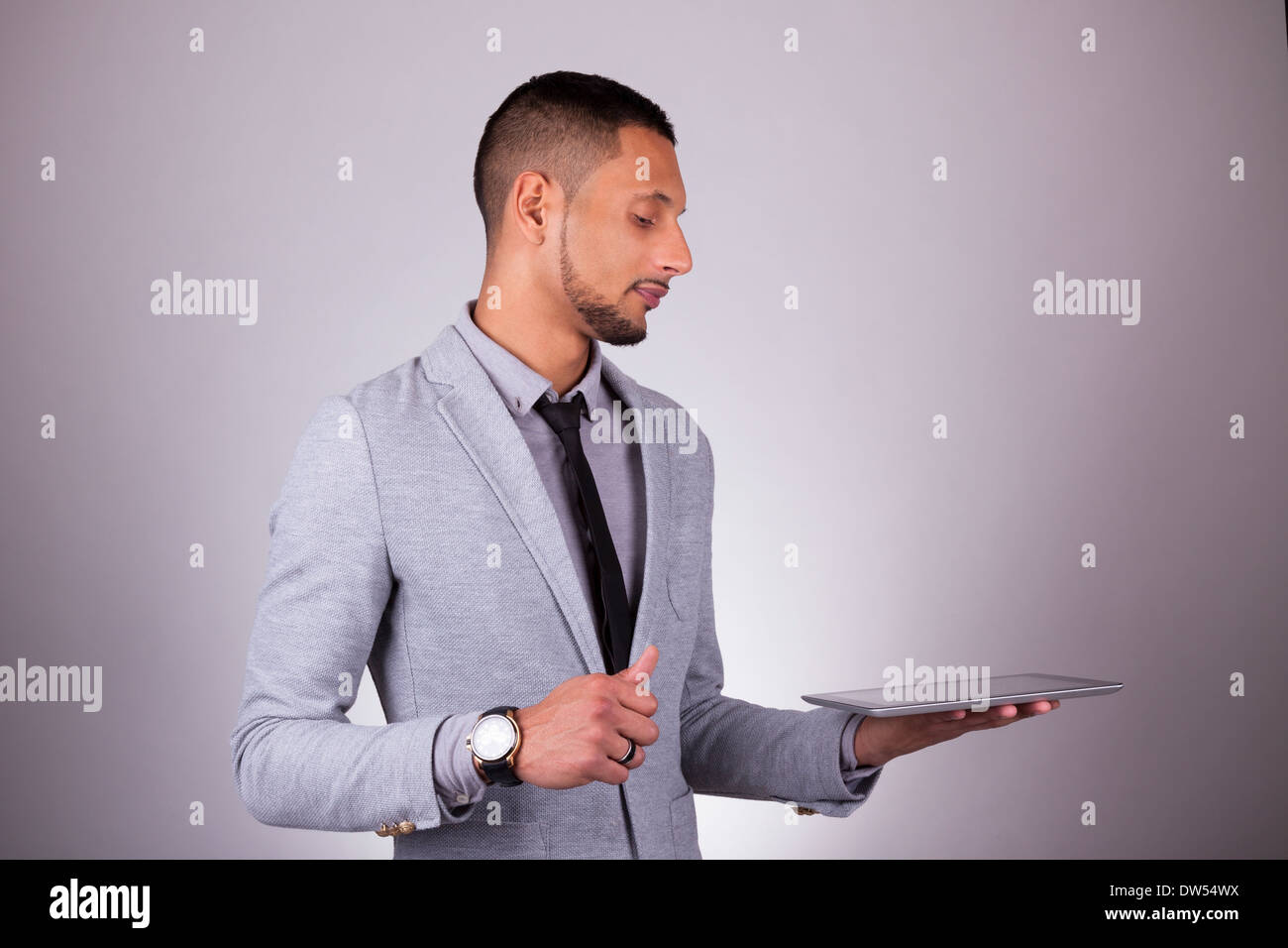 African American business man using a tactile tablet - Black people, over gray background Stock Photo