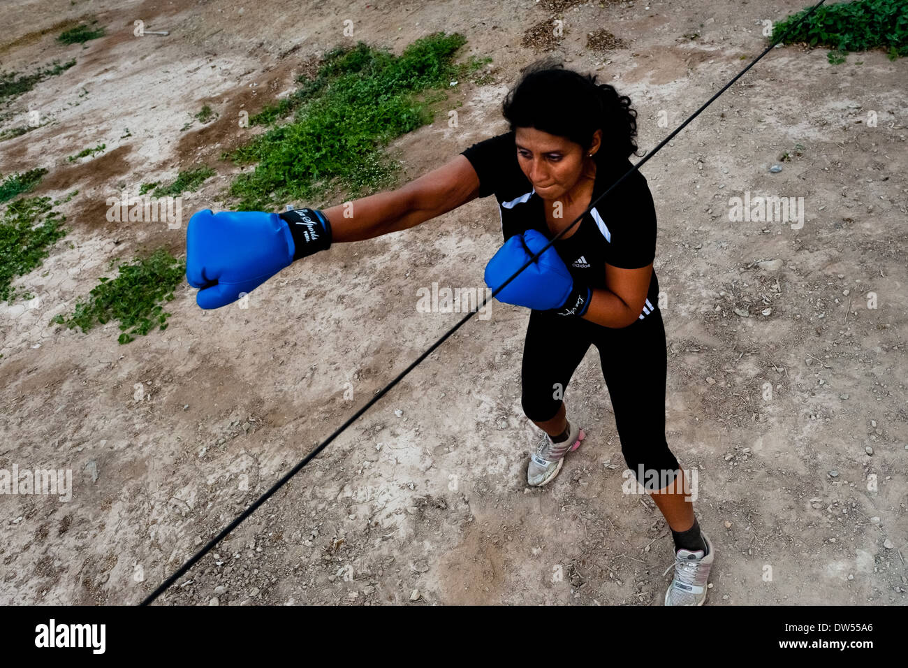 A Peruvian woman practices punching and movement while training in the outdoor boxing school in Callao, Peru. Stock Photo