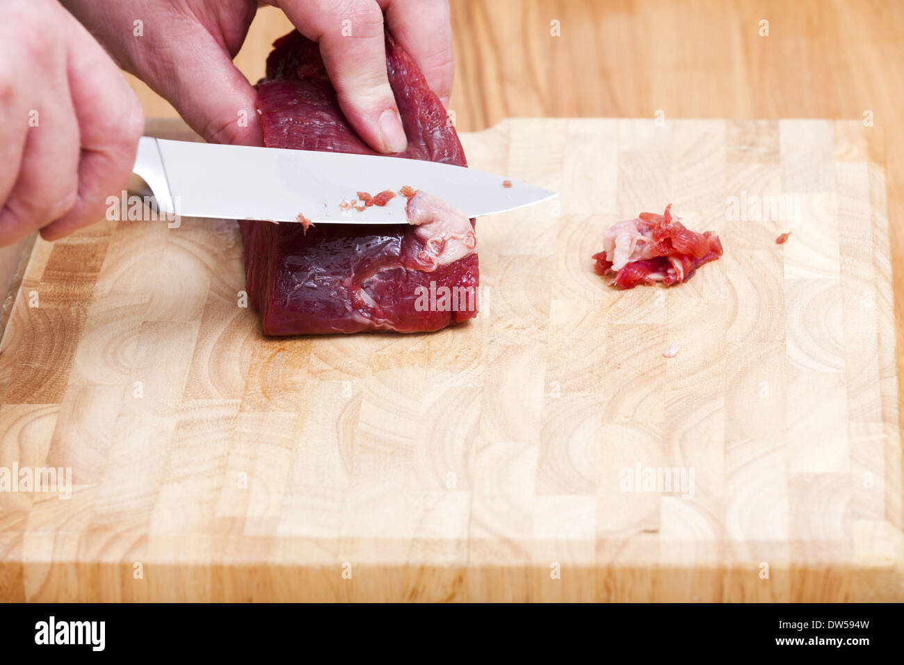 With a sharp kitchen knife cut off the fat from a piece beef tenderloin