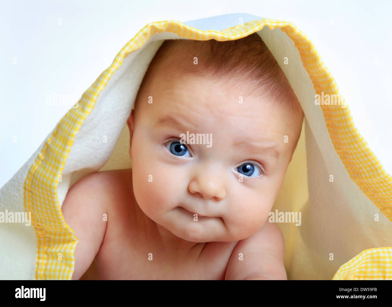 Baby girl under a white and yellow blanket, isolated on white background Stock Photo