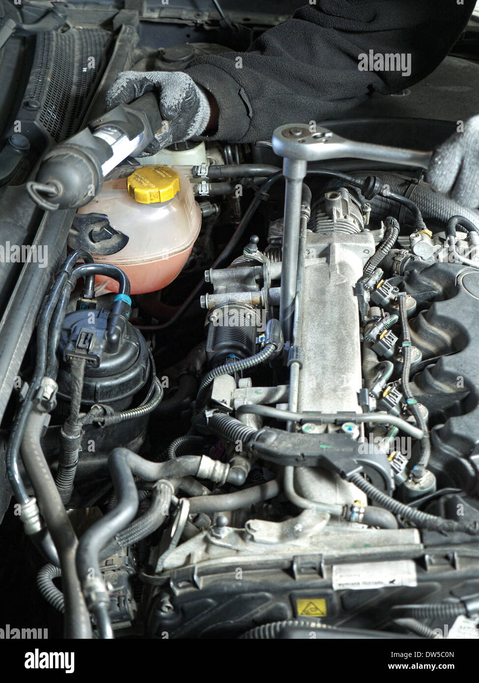 Auto mechanic replacing glow plugs in car diesel engine using spark plug spanner Stock Photo