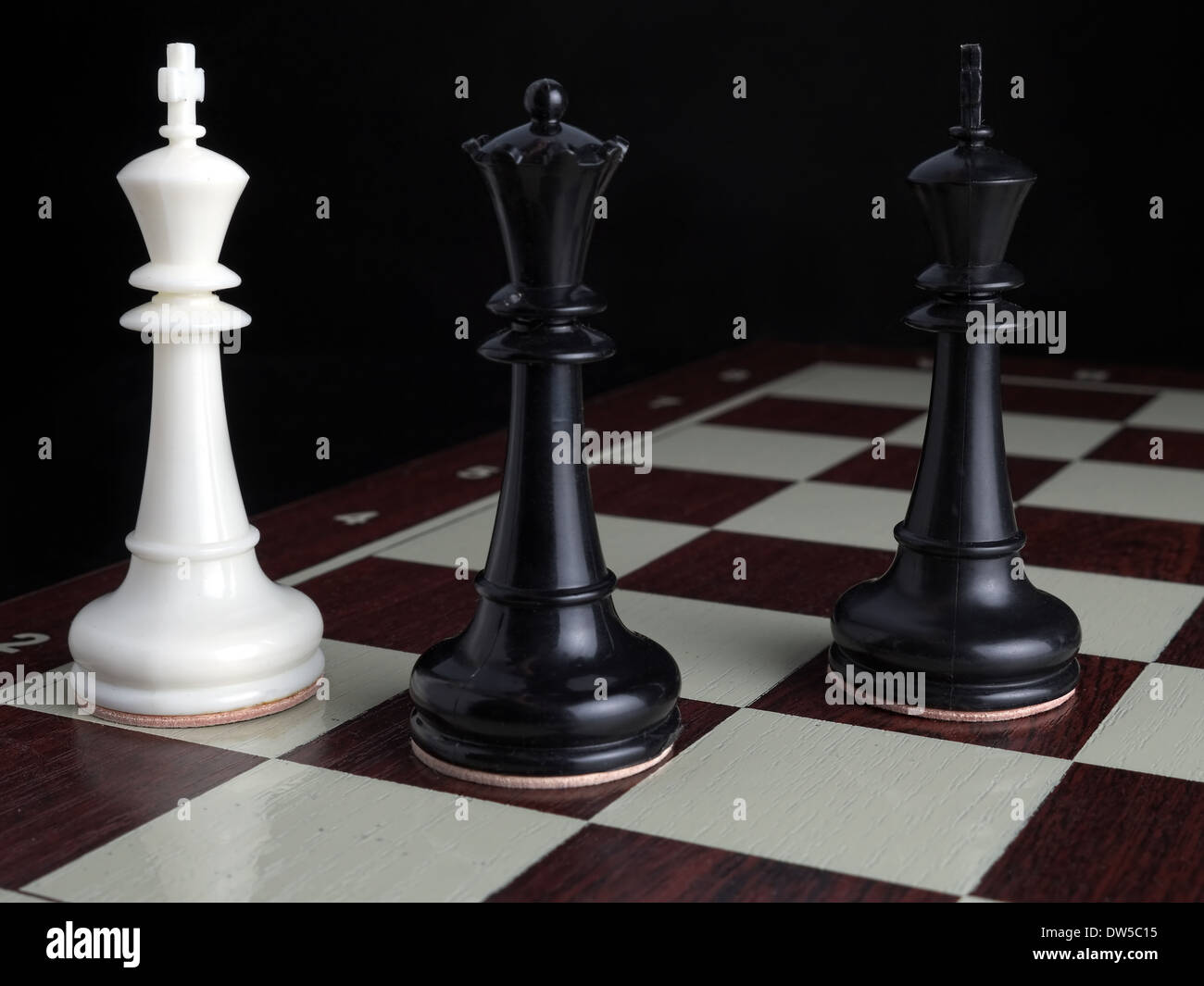 White King checkmated by black Queen with Black King on chessboard Stock Photo