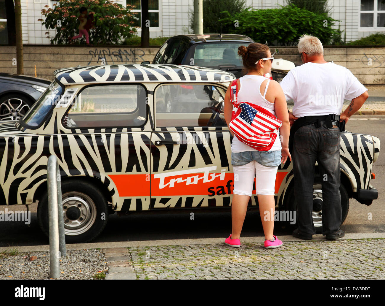 Tourists stand at an East German Trabant car near Checkpoint Charlie in Berlin, August 08, 2013. More and more tourists come to the German capital every year. The photo is part of a series on tourism in Berlin. Photo. Wolfram Steinberg dpa Stock Photo