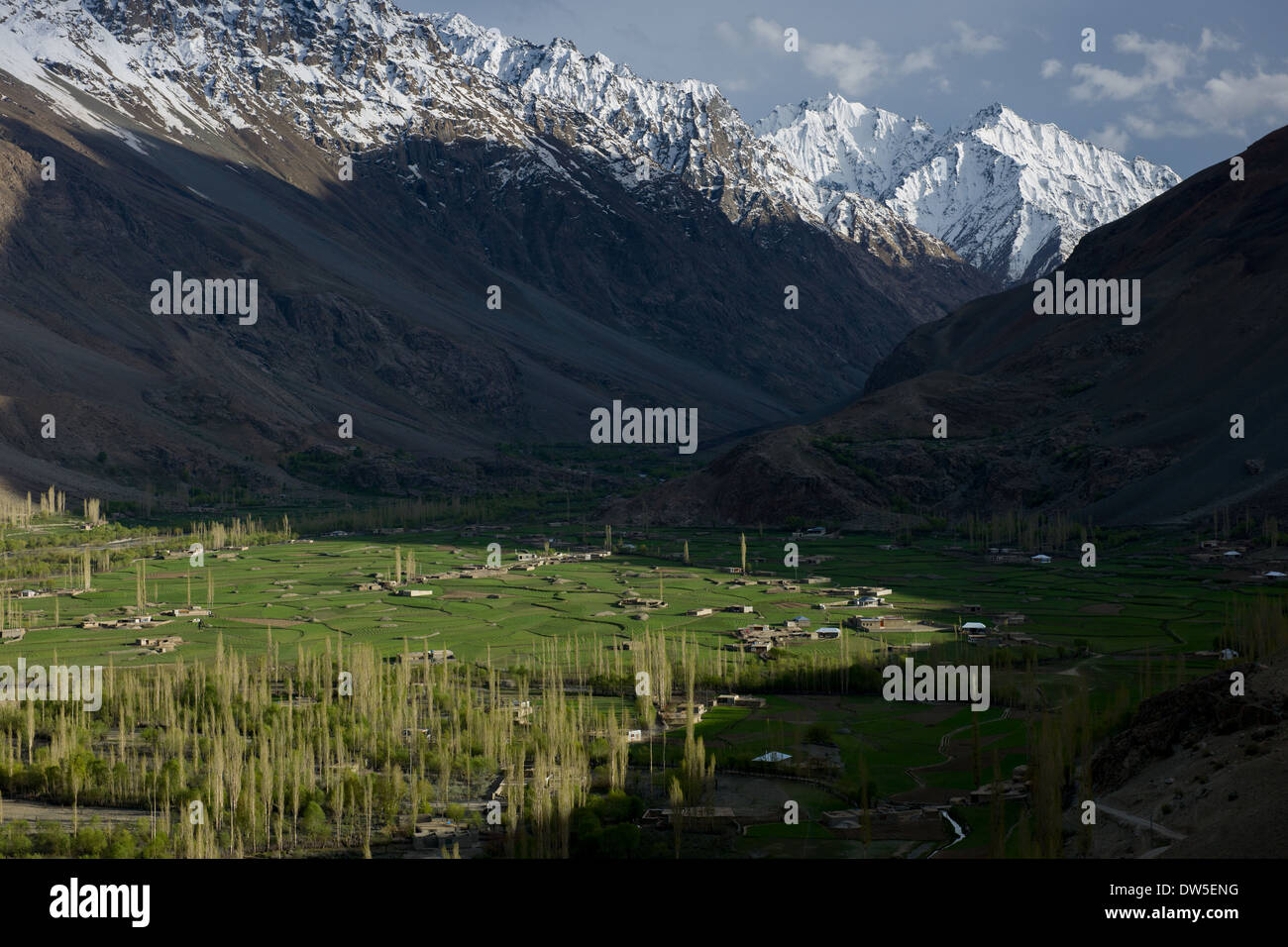 Snow-capped mountains towering over the verdant Ghizar River (Gilgit River) Valley near Kinisotek, seen from the Shandur-Gilgit Road, near the Shandur Pass, Gilgit-Baltistan, Pakistan Stock Photo