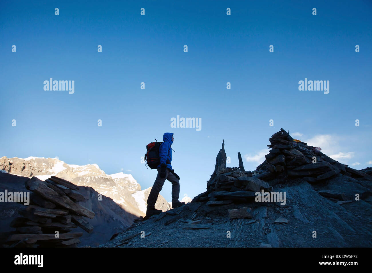 silhouette of hiker climbing mountain peak at sunrise Stock Photo