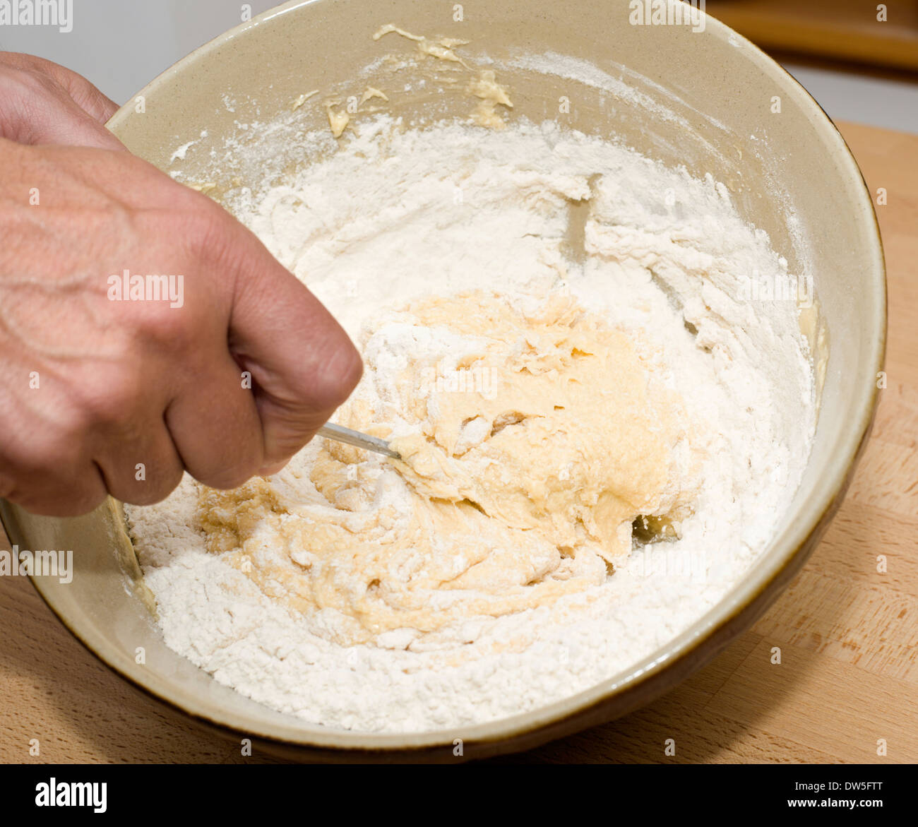 Adding flour to creamed ingredients in a mixing bowl for a sponge cake