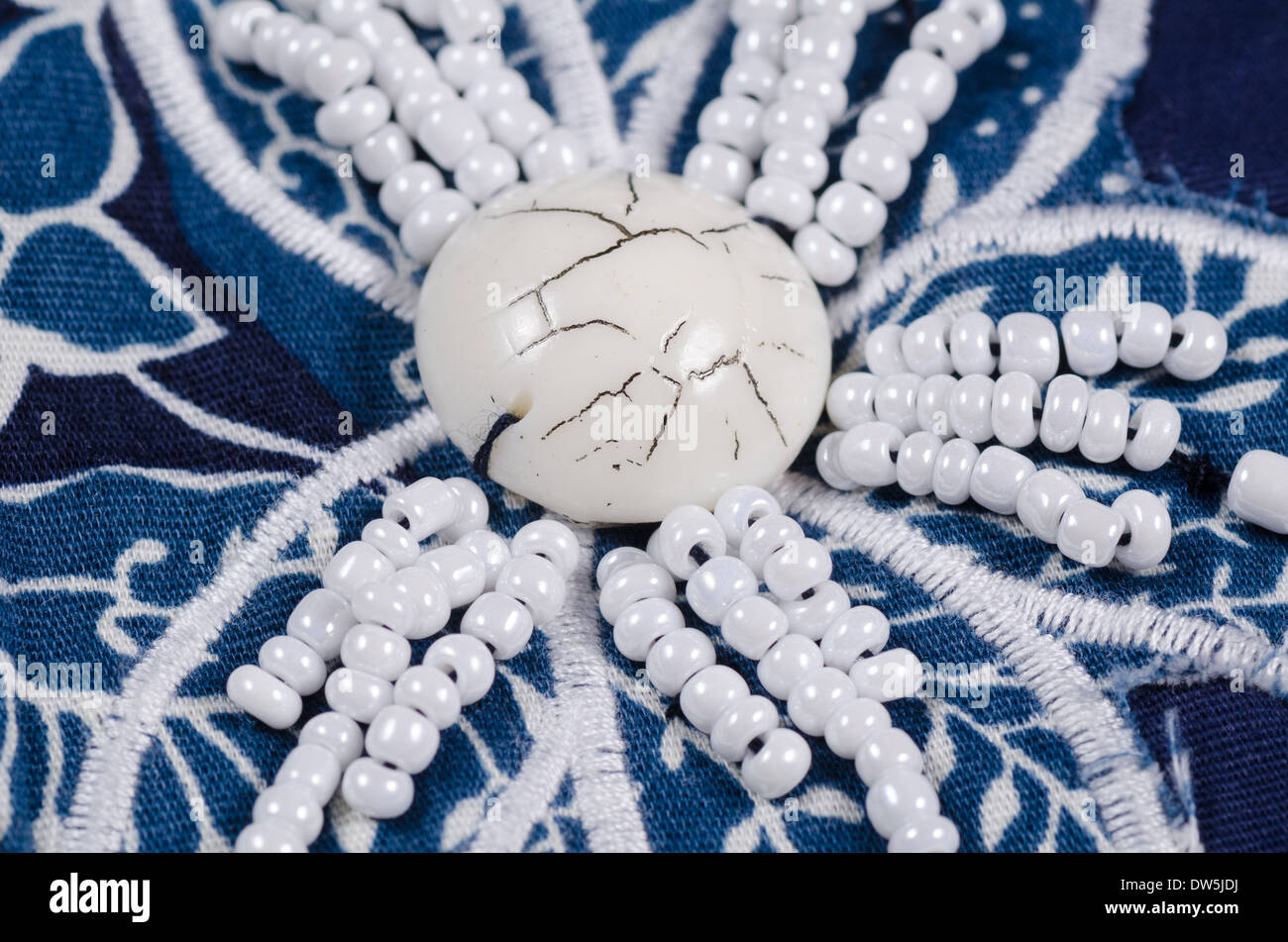 Embroidered flower shaped bead pattern on blue fabric Stock Photo