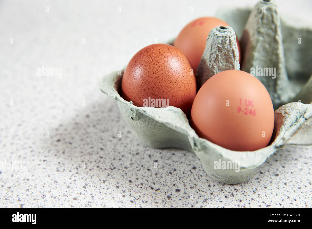 3 eggs in an egg box await preparation in a kitchen Stock Photo