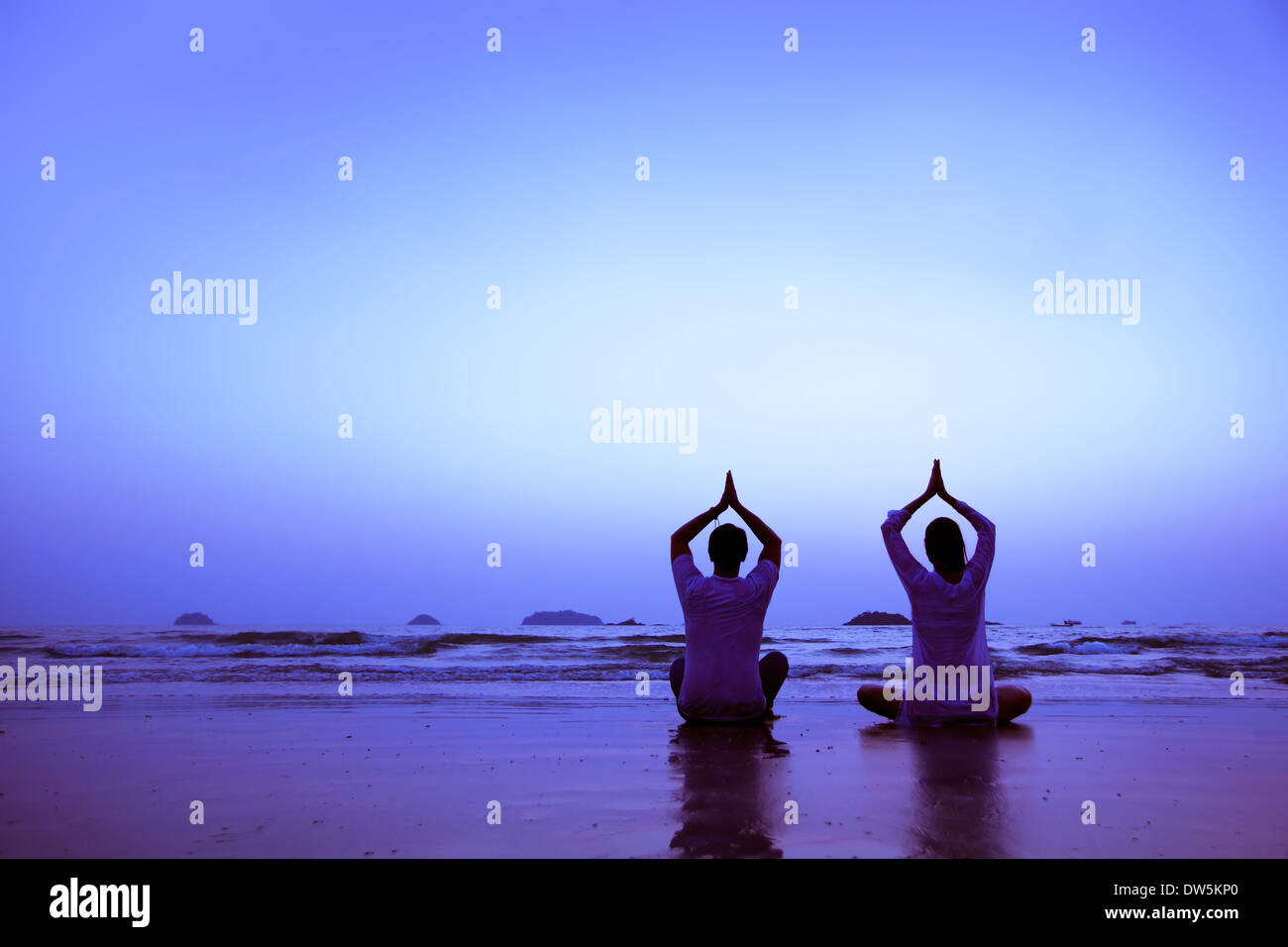 family yoga on the beach at sunset Stock Photo