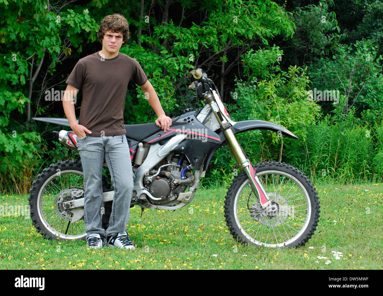 attractive teenage boy standing beside dirt bike Stock Photo