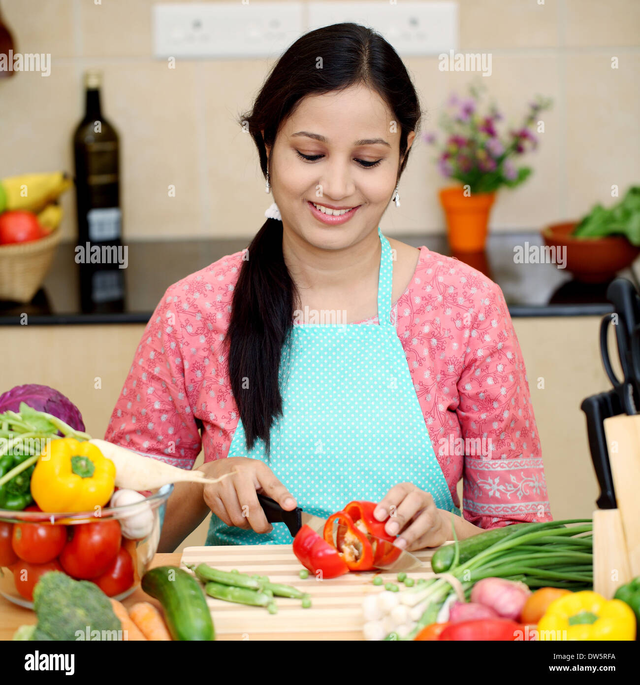 Smiling young Indian woman cutting vegetables Stock Photo - Alamy